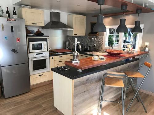 Il comprend une cuisine équipée d'un réfrigérateur et d'un comptoir avec des chaises. dans l'établissement La Maison des Délices, au Beausset