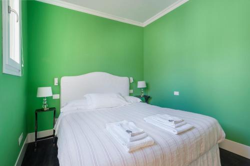 a green bedroom with a bed with towels on it at Green House city center in Bologna
