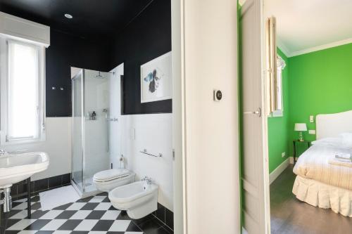 La salle de bains est pourvue de murs verts et noirs, de toilettes et d'un lavabo. dans l'établissement Green House city center, à Bologne