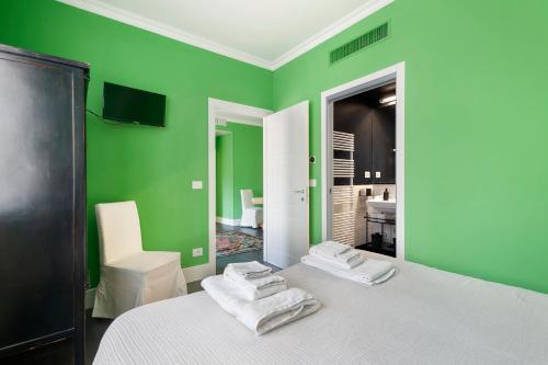 a green room with a bed with towels on it at Green House city center in Bologna
