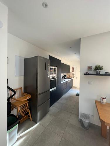 une cuisine avec un réfrigérateur en acier inoxydable et une table dans l'établissement Le Séjour qu'on M, à Le Cateau