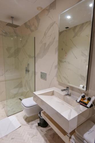 a bathroom with a sink and a toilet and a shower at Hotel Miramare in Vlorë