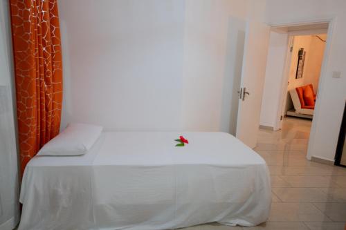a bedroom with a white bed with a flower on it at Praslin Paradise in Baie Sainte Anne