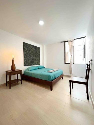 ein Schlafzimmer mit einem Bett, einem Tisch und einem Stuhl in der Unterkunft Moderno Apto con Vista a la Basílica in Buga