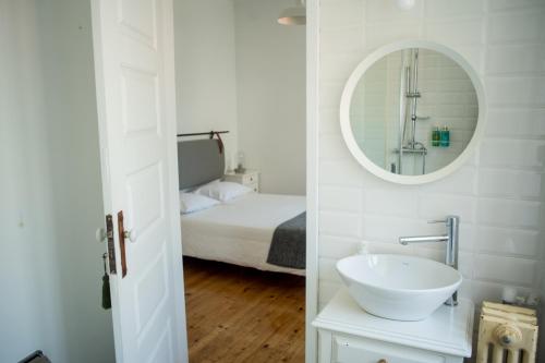 a bathroom with a sink and a bed and a mirror at 3 Marias Residence in Viana do Castelo