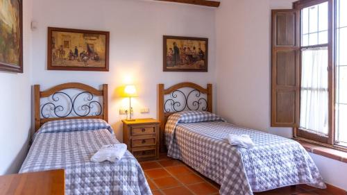 a bedroom with two beds and a table and a window at Finca la Cañera Alcalá de Guadaira by Ruralidays in Alcalá de Guadaira