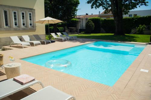 a swimming pool with chairs and an umbrella at 3 Marias Residence in Viana do Castelo