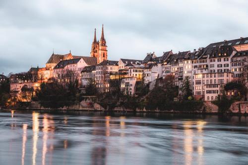a group of buildings on a hill next to a river at Holiday Inn Express & Suites - Basel - Allschwil by IHG in Basel