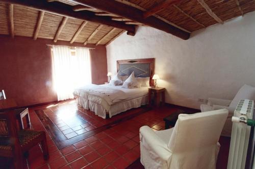 a bedroom with a bed and chairs in a room at Del Amauta Hosteria in Purmamarca