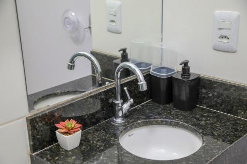 a bathroom counter with a sink with two faucets at Casa Pequena, Completa e Aconchegante - Tiny House in Palmas