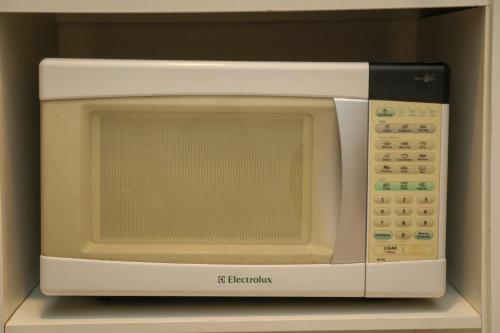 a white microwave oven sitting on top of a shelf at Casa Pequena, Completa e Aconchegante - Tiny House in Palmas
