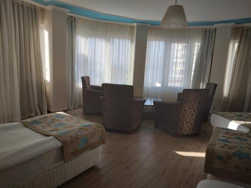 um quarto de hotel com uma cama, cadeiras e janelas em Cender Hotel em Antalya