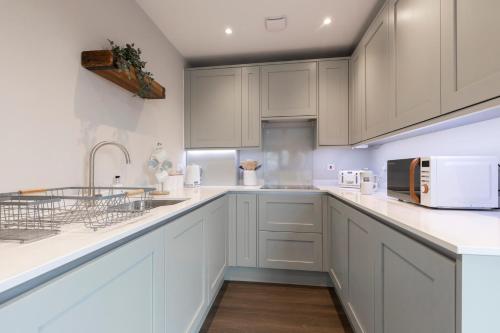 una cocina blanca con armarios blancos y fregadero en Elliot Oliver - Stunning Three Bedroom Penthouse With Large Terrace & Parking en Gloucester
