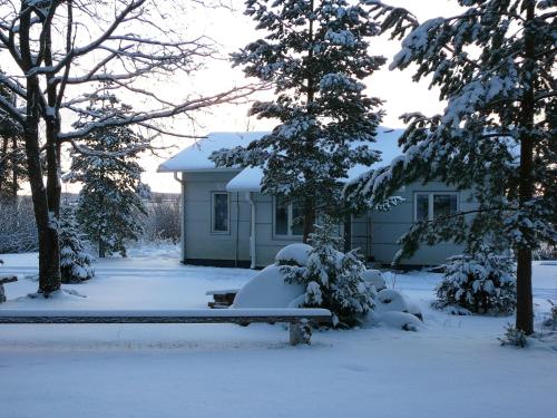 a snow covered bench in front of a house at Levomäki Farm Cottages in Ypäjä