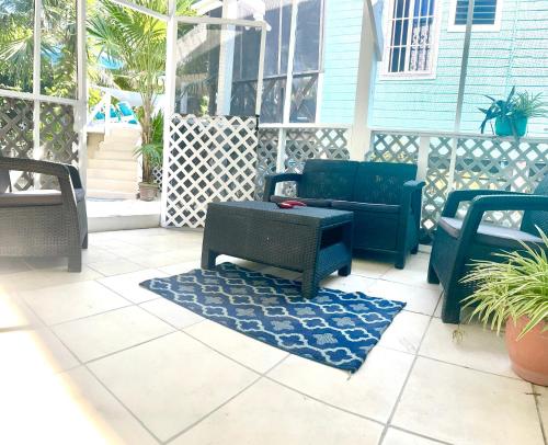 a porch with chairs and a table and a rug at Hummingbirds Cabins in Caye Caulker