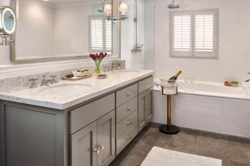 a white bathroom with two sinks and a tub and a tubermottermott at The Estate Yountville in Yountville