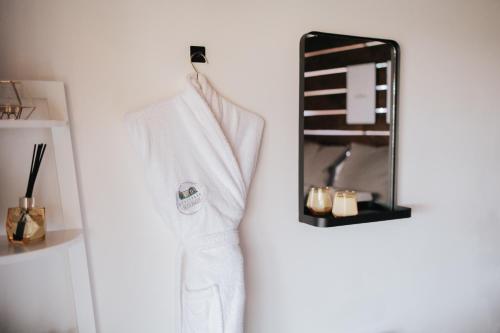 a white robe hanging on a wall next to a mirror at Horse Park Hideaway, Luxury Hot Tub Glamping Retreat in Pilling