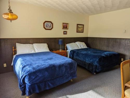 two beds in a hotel room with blue sheets at Crossroads motel & cabins in Oxford