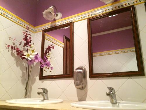 a bathroom with two sinks and two mirrors and flowers at El Porton de la Huebra in Vecinos