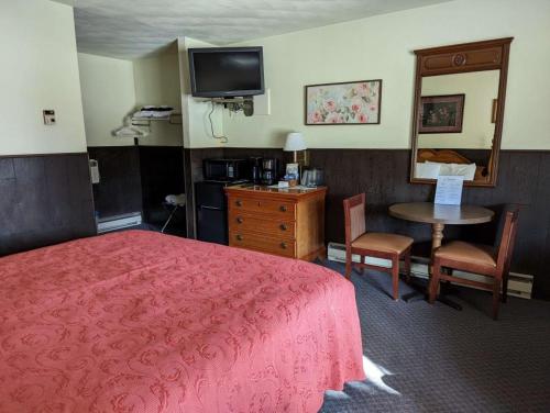 a hotel room with a bed and a table and a mirror at Crossroads motel & cabins in Oxford