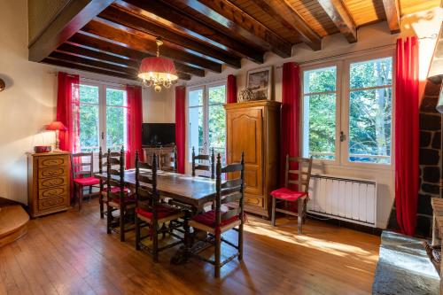 une salle à manger avec une table en bois et des rideaux rouges dans l'établissement Chalet des Melezes, à Font-Romeu-Odeillo-Via