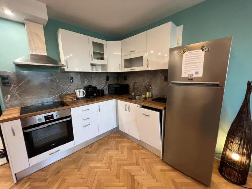 a kitchen with white cabinets and a stainless steel refrigerator at Al Malina City Family Apt with Parking Space in Sofia