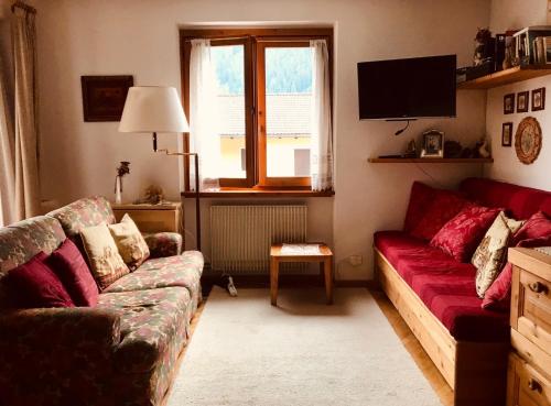 a living room with a couch and a tv at Appartamento Il nido in Carisolo