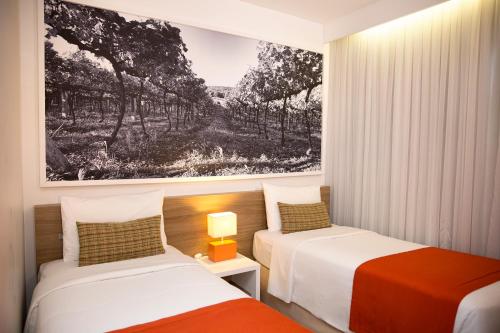 a bedroom with two beds and a picture on the wall at Partner Caxias do Sul in Caxias do Sul
