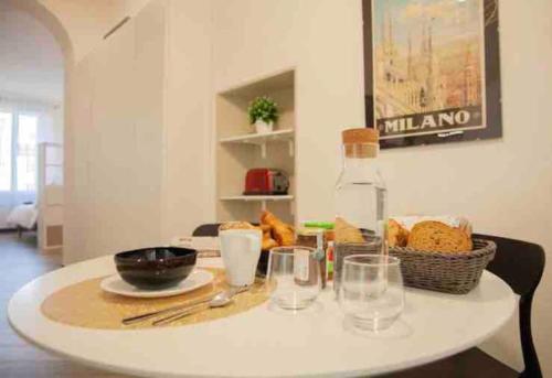 una mesa blanca con algo de comida y vasos. en Glamour Liberty Apartment Sabotino38, en Milán