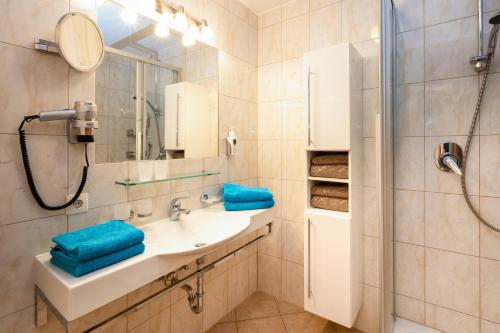 een badkamer met een wastafel en een douche met blauwe handdoeken bij Apart Albore in Ischgl