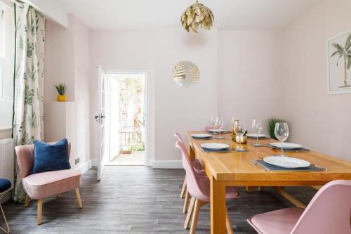a dining room with a wooden table and pink chairs at Cloisters Cottage in Chichester
