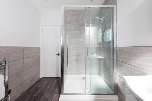 a shower with a glass door in a bathroom at Cloisters Cottage in Chichester