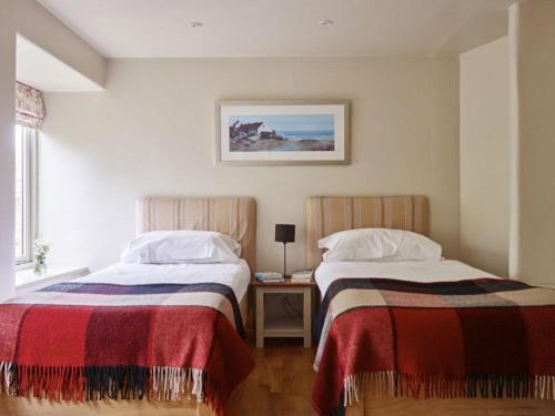 a bedroom with two beds and a table with a lamp at Yennadon Barn in Totnes