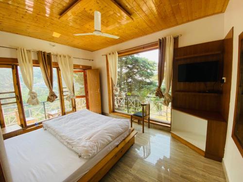 a bedroom with a bed and a large window at Hotel Himalayan Village in Mussoorie