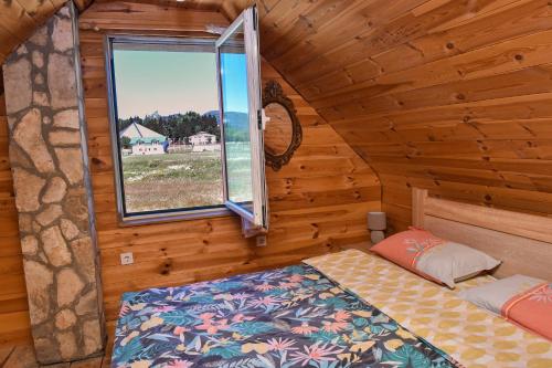 a bedroom with a bed and a window in a log cabin at Holiday Home Jakov in Kolašin