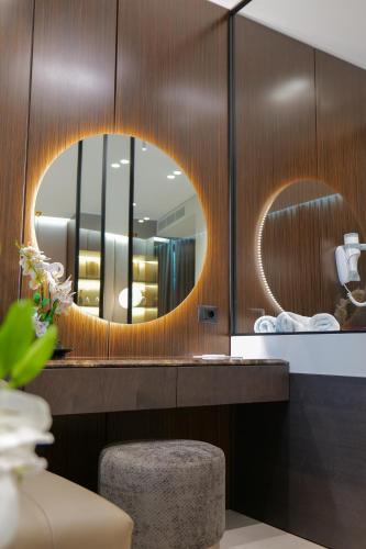 a bathroom with a circular mirror and a stool at Hotel Miramare in Vlorë