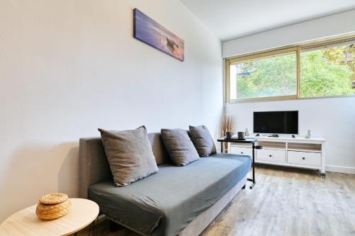 a living room with a couch and a tv at Paradis Prado furnished apartment in Marseille