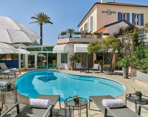 - une piscine avec des tables et des parasols en face de l'hôtel dans l'établissement Hotel Le Suquet Cannes, à Cannes