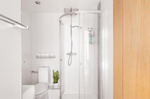 a white bathroom with a shower and a toilet at Riverside Balcony Apartments, 10 minutes from Oxford Circus in London