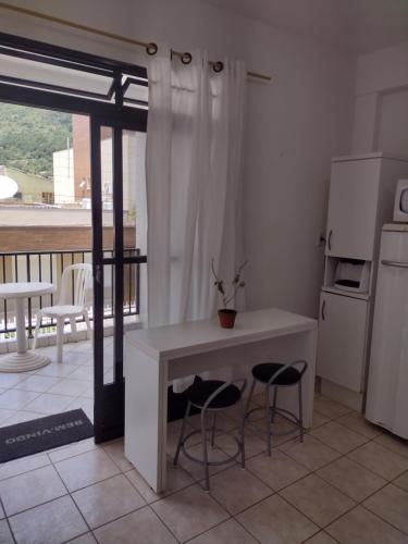 a kitchen with a table and two stools in a room at Apto Rua da Praia in Florianópolis