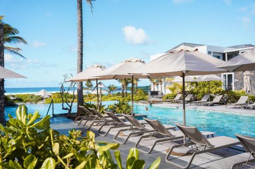 a pool at the resort with lounge chairs and umbrellas at Constance Le Chaland IKO Mauritius in Blue Bay