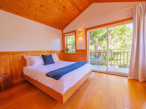 a bedroom with a bed and a large window at The Perch Modern 2 Bed Cabin with Patio and Hot Tub in Ucluelet