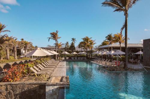 藍海灣的住宿－Anantara Iko Mauritius Resort & Villas，度假村的游泳池,配有椅子和遮阳伞