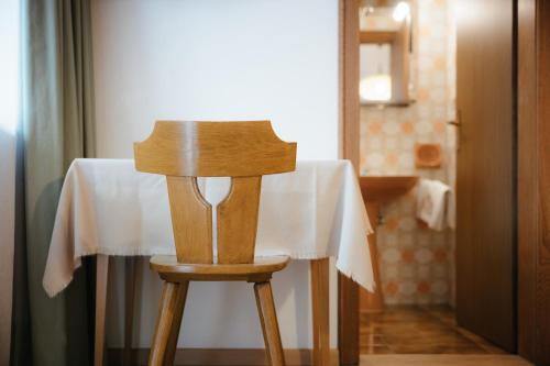 a wooden chair sitting at a table with a white table cloth at Residence Arche Noah - Colfosco in Colfosco
