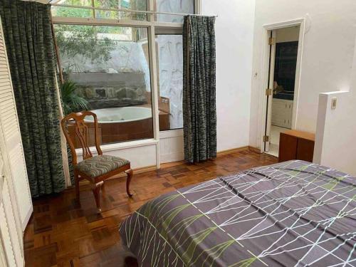 um quarto com uma cama, uma janela e uma cadeira em Apartamento de lujo con jardines paisajísticos em La Paz