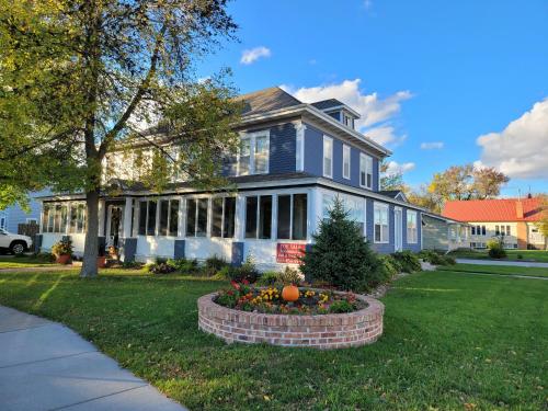 ein blaues Haus mit einem Blumenbett davor in der Unterkunft Prairie House Manor Bed and Breakfast in De Smet