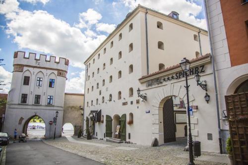 a large white building with an archway in a street at Hotel Spichrz in Toruń