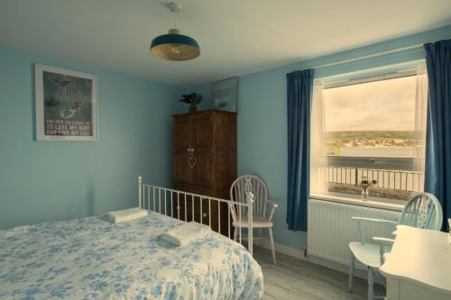 sypialnia z niebieskimi ścianami, łóżkiem i oknem w obiekcie 1 Quayside Court w mieście Swanage