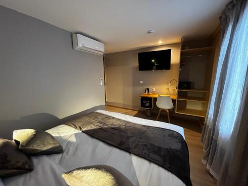a bedroom with a bed and a desk and a tv at 9WAGRAM Hotel Boutique in Le Mans