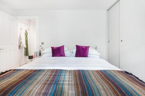 een slaapkamer met een groot bed met paarse kussens bij Chepstow Place- Notting Hill in Londen